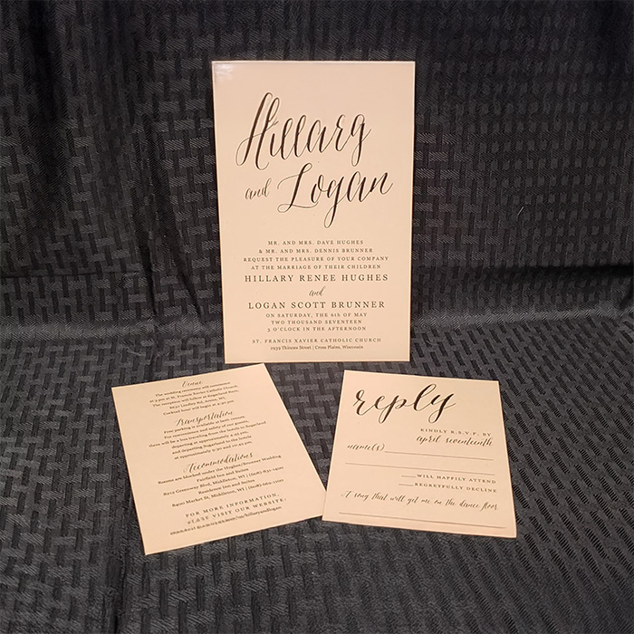 A beige wedding invitation set displayed on a textured dark gray background, featuring the main invitation, a details card, and a reply card for Hillary and Logan.